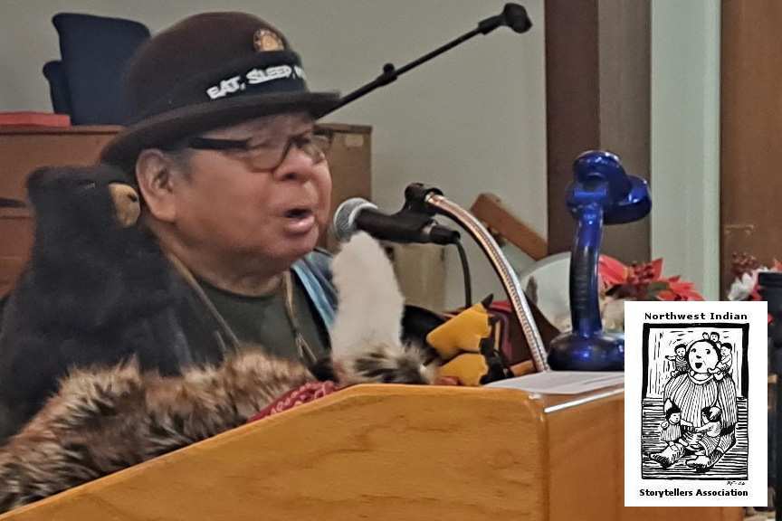 Storyteller Ed Edmo shares a story at the podium, alongside the Northwest Indian Storytellers Association logo